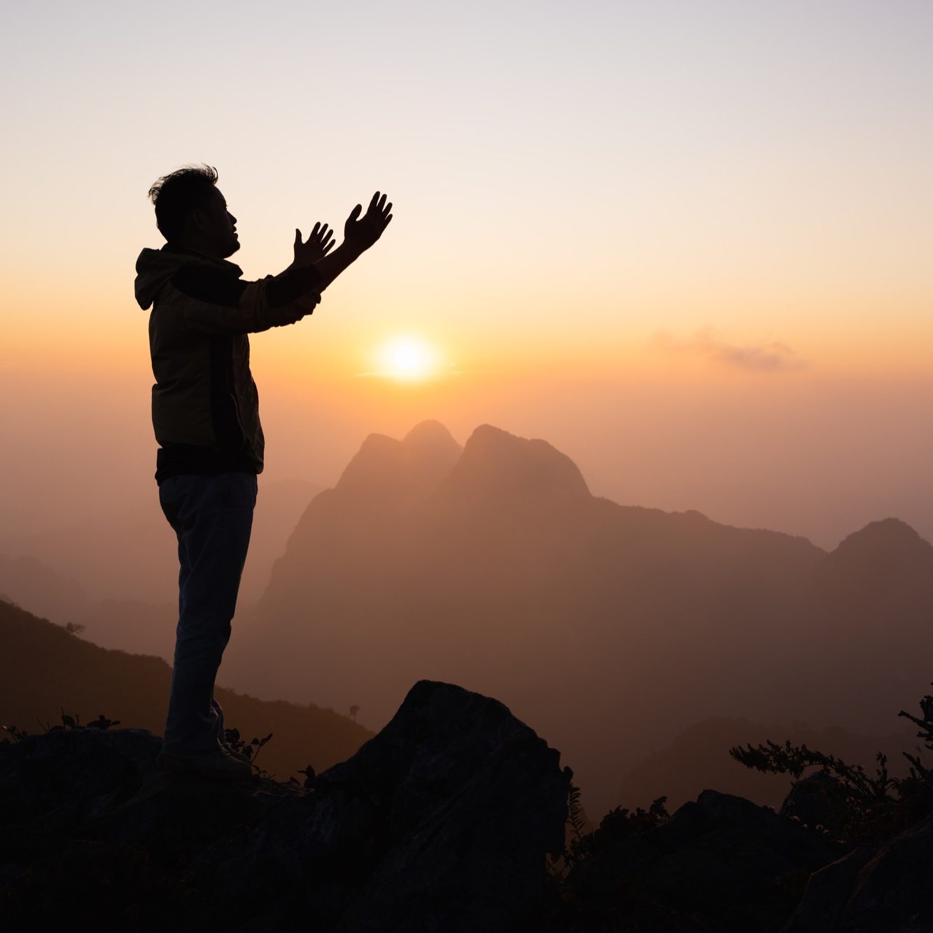 Man praying in front of a mountain